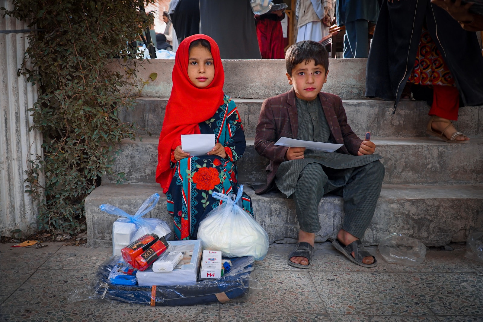 a boy and a girl sitting on the steps of a building